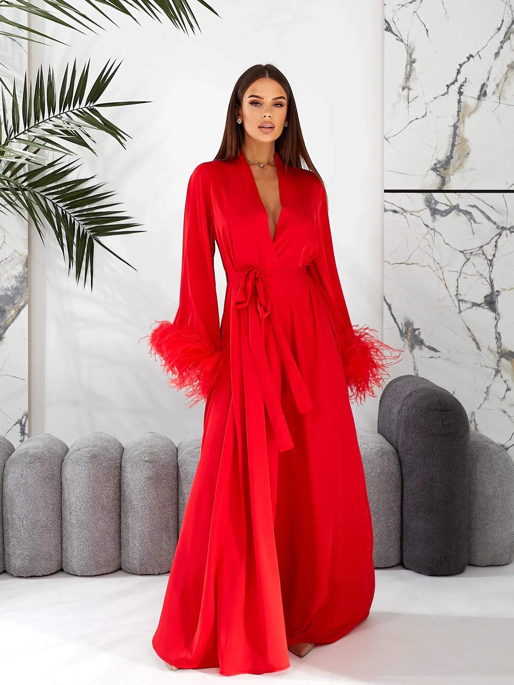 Woman wearing long red silk bridal robe with feather cuffs, perfect for wedding morning