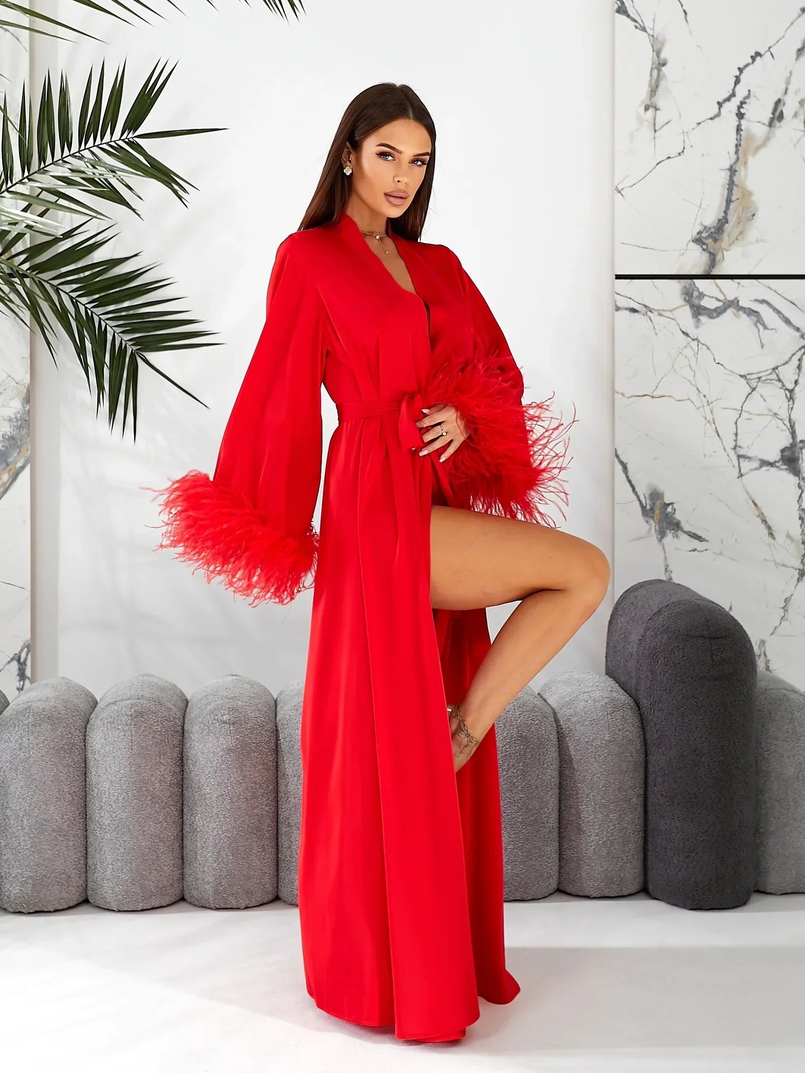 Woman wearing red silk bridal robe with feather trim, perfect for wedding morning.