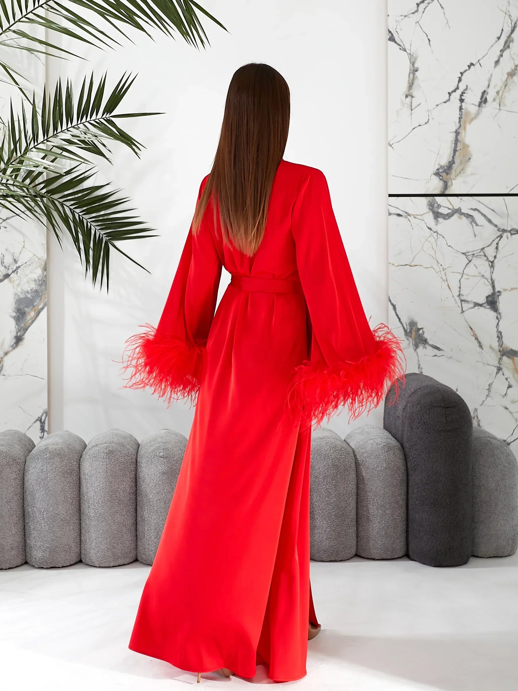 Woman in red silk bridal robe with feather cuffs, perfect for wedding morning