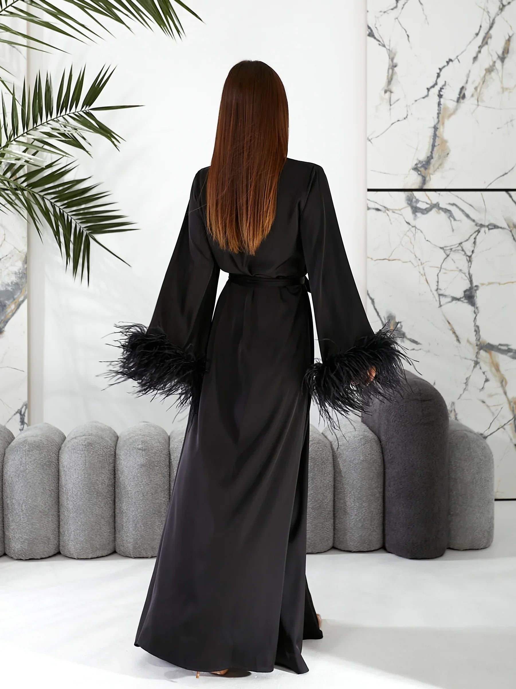 Back view of woman in long black silk bridal robe with feathered sleeves, wedding morning style