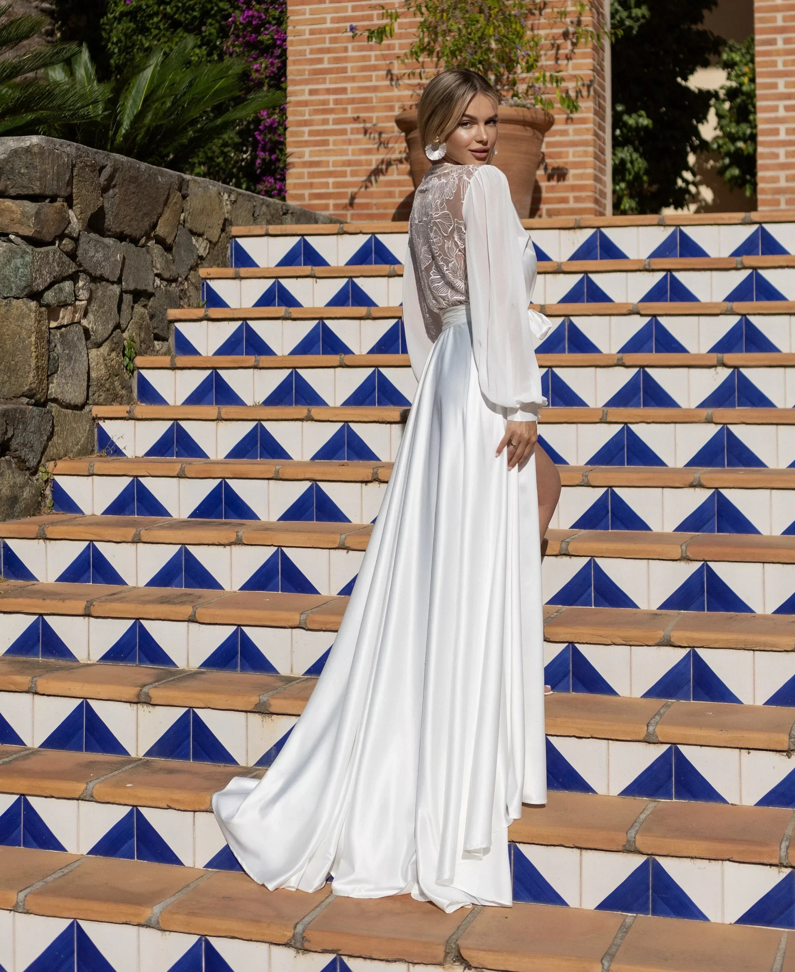 Bride in white silk and sheer lace bridal robe on tiled steps, perfect for wedding morning.