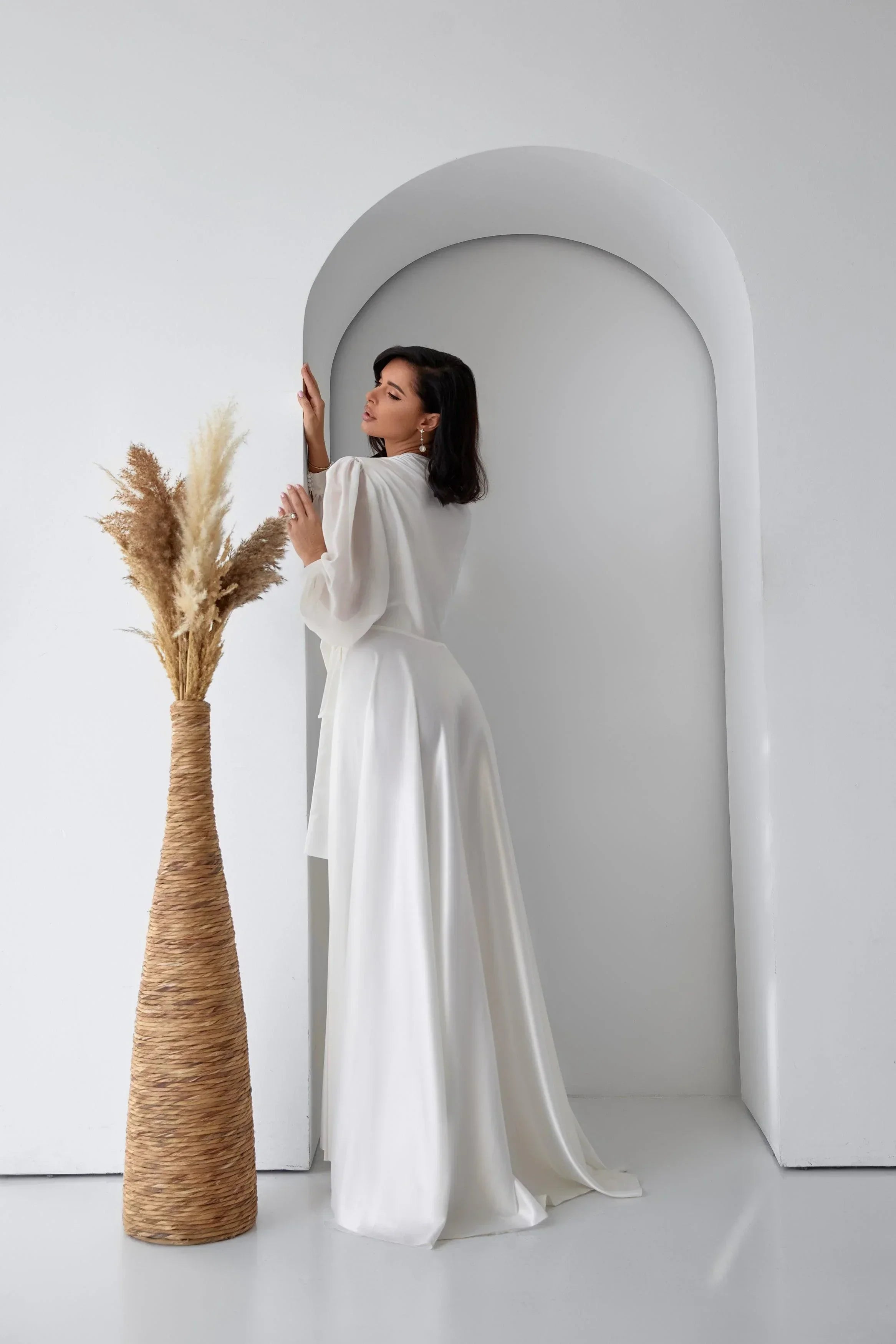 Bride in long white silk bridal robe with sheer sleeves, perfect for wedding morning.