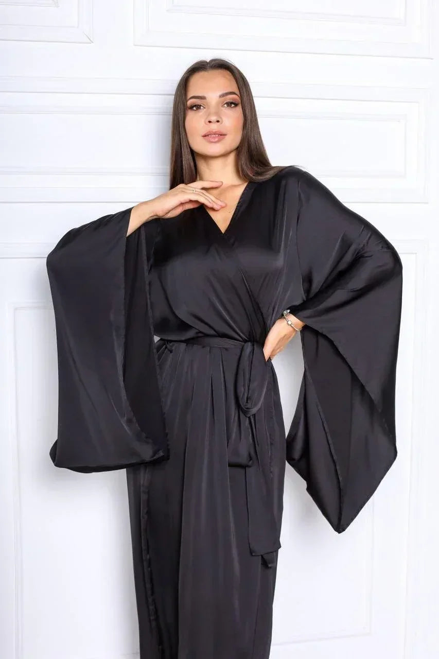 Woman wearing a black silk bridal robe with wide sleeves, perfect for wedding morning.