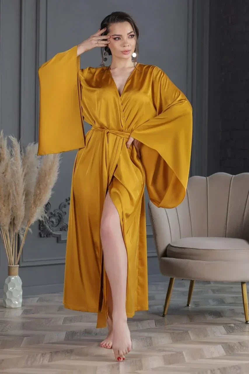 Woman in golden silk bridal robe with wide sleeves, perfect for wedding morning elegance.