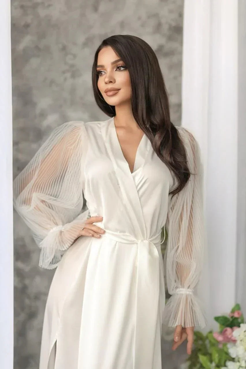 Bride in white silk bridal robe with sheer lace sleeves, perfect for wedding morning.