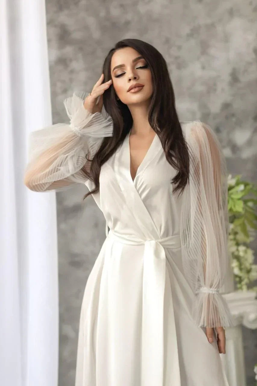 Bride wearing white silk bridal robe with sheer lace sleeves, perfect for wedding morning.