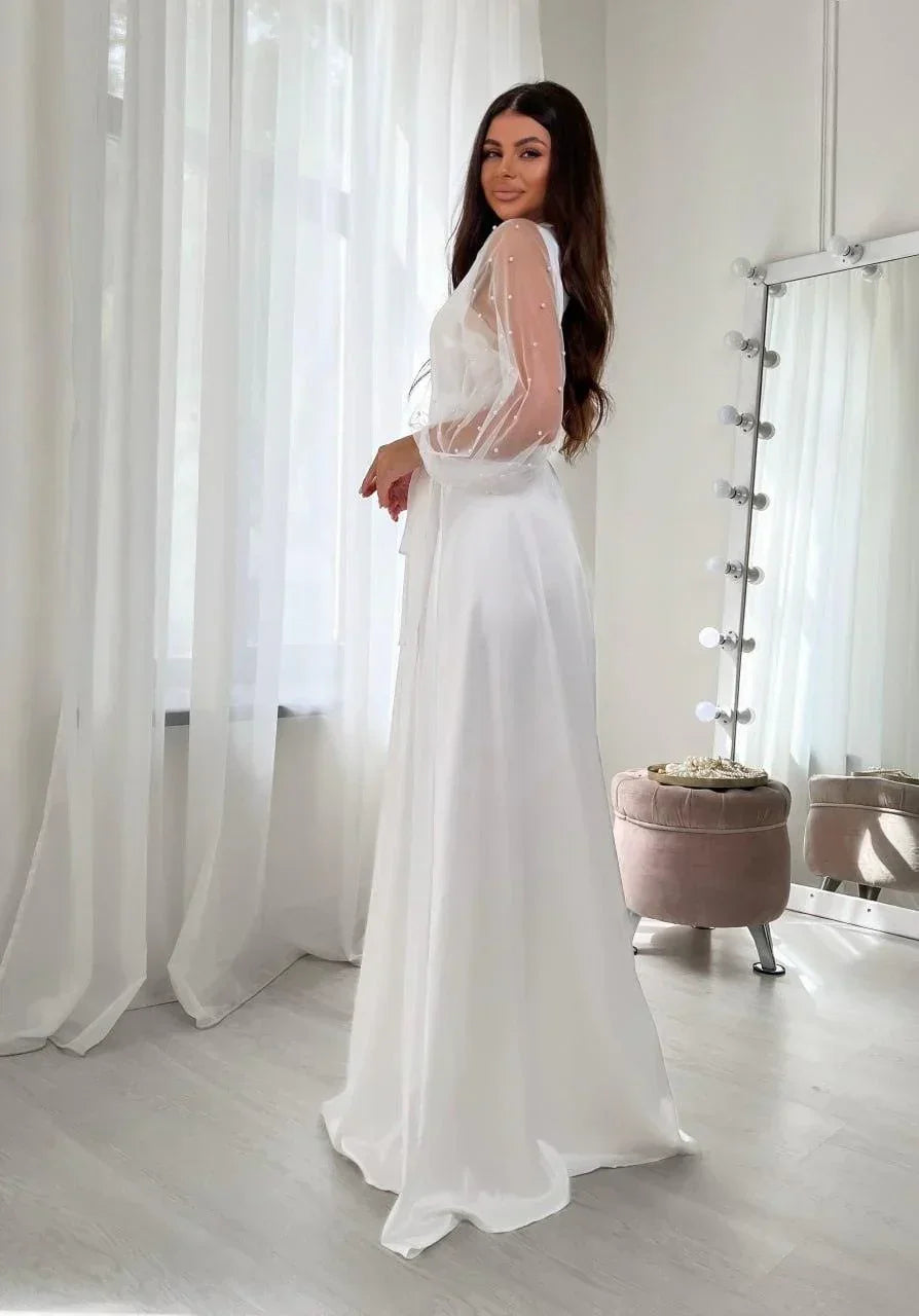 Bride in long white silk bridal robe with sheer pearl lace sleeves for wedding morning